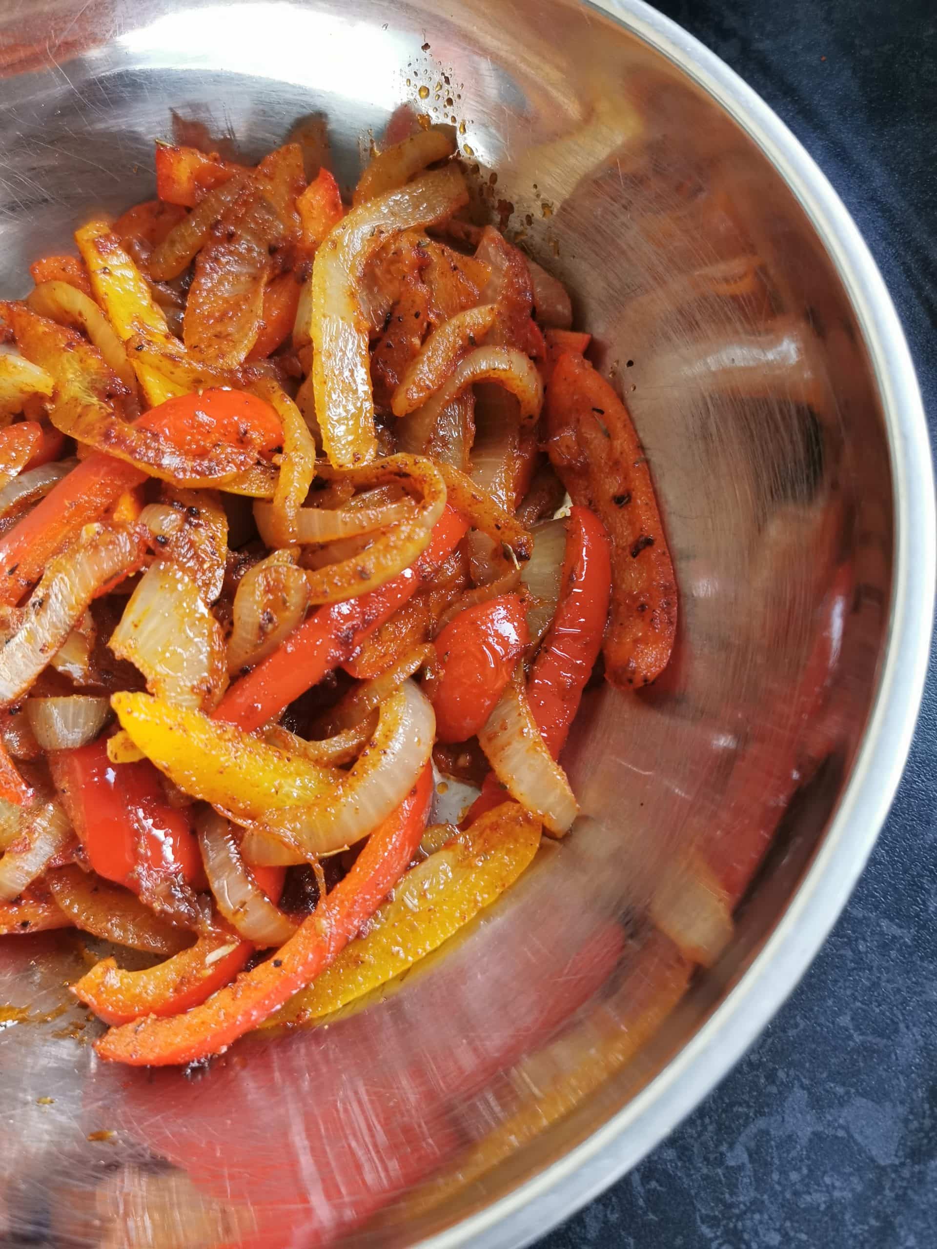 Cooked onions and peppers in a silver bowl
