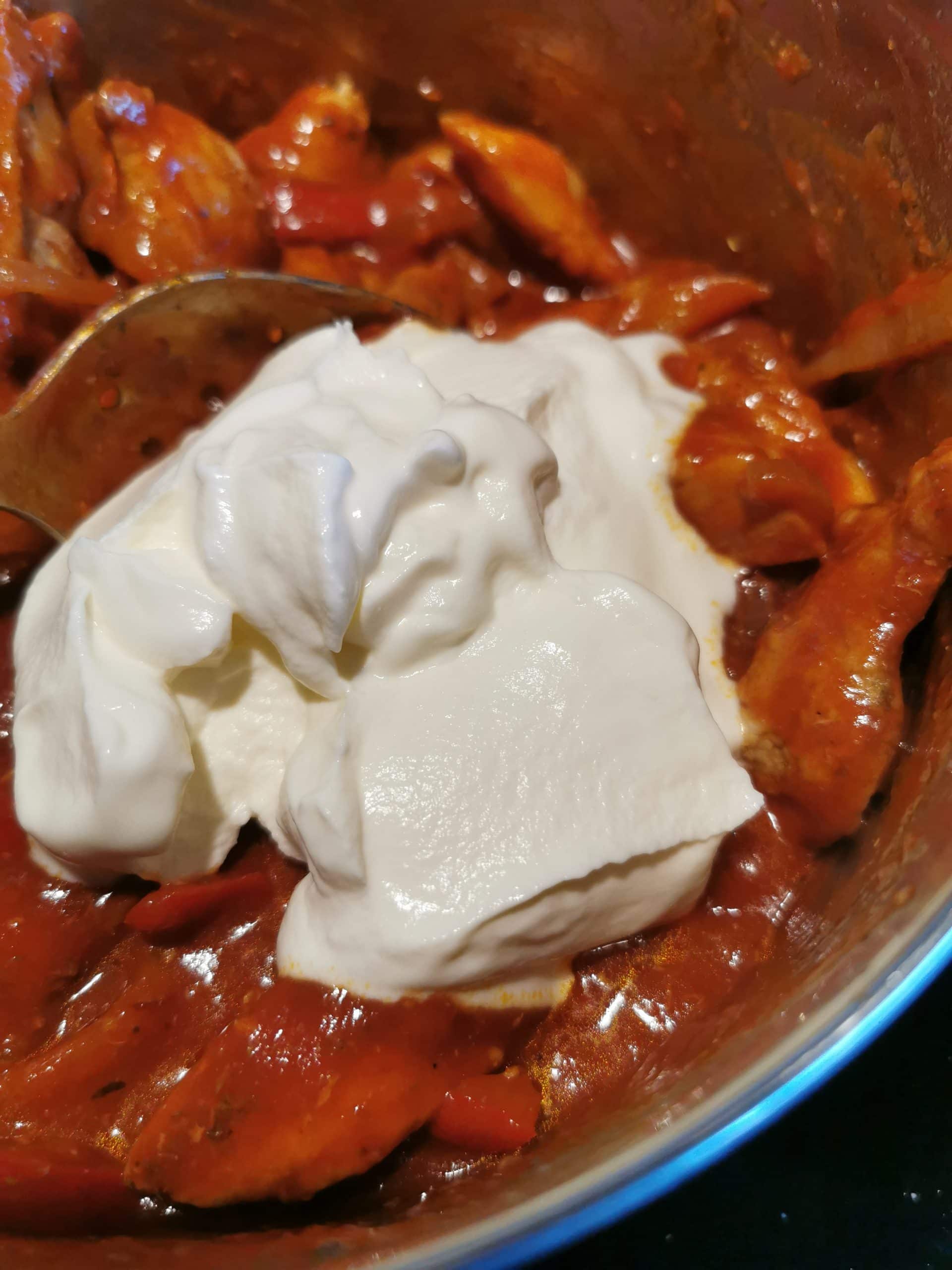 a pan of chicken, onions, peppers, tomato passata and sour cream in a large saucepan