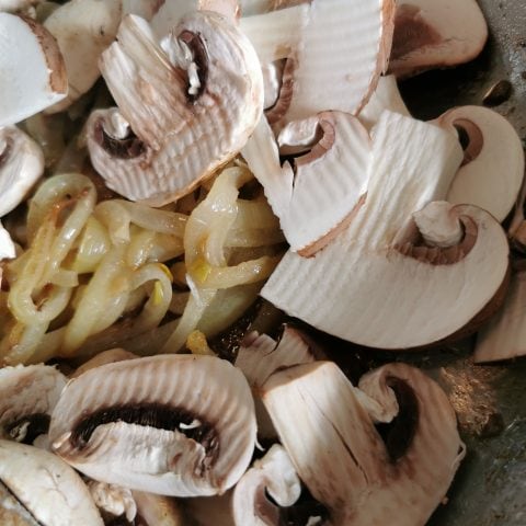 Onions and mushrooms cooking in a frying pan