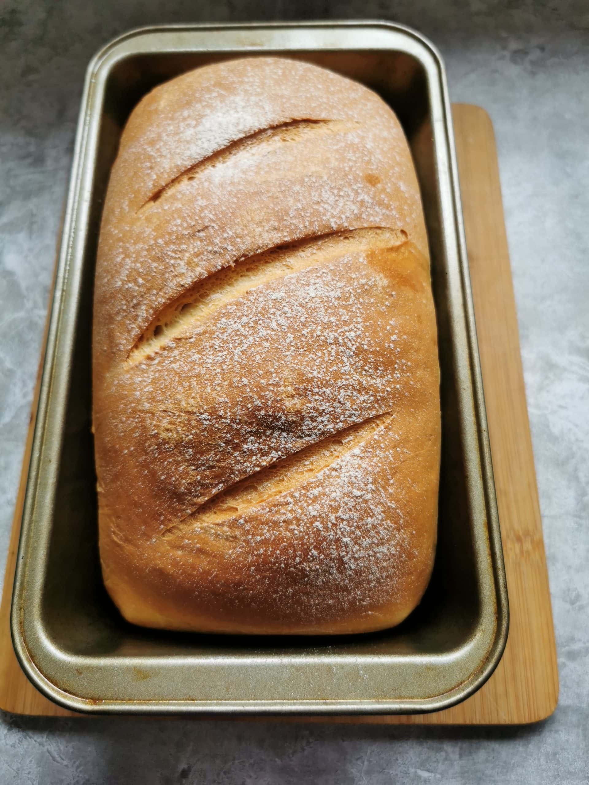 A freshly made soft white loaf in a loaf tin