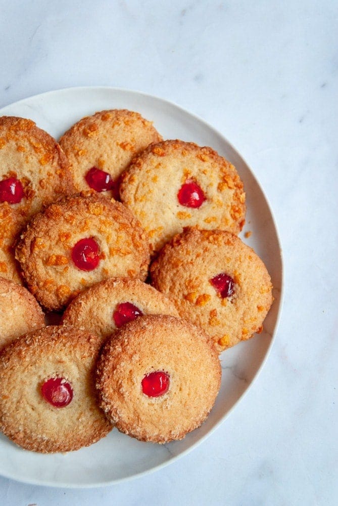 A plate of cornflake topped biscuits with a glace cherry in the middle 