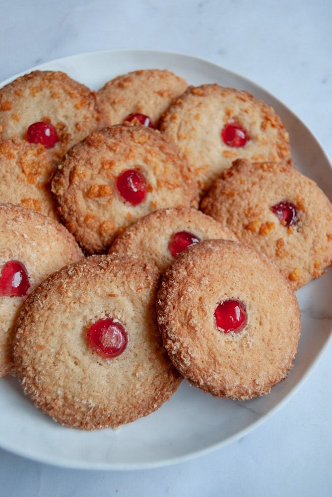 A plate of melting moment biscuits topped with a glace cherry