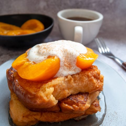 4 slices of French brioche toast topped with peaches and Greek yoghurt