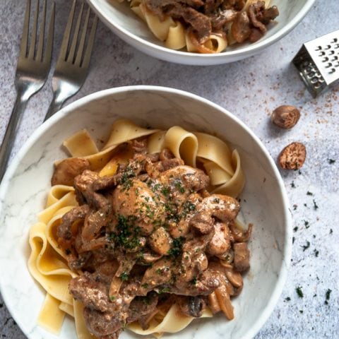 A bowl of beef stroganoff with mushrooms and egg noodles.