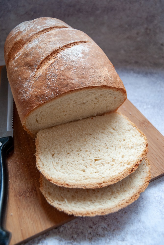 A homemade loaf of bread dusted with flour on a wooden chopping board