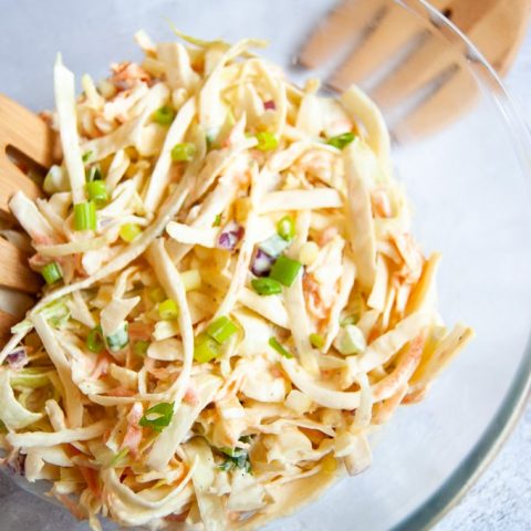 A bowl of coleslaw topped with spring onions