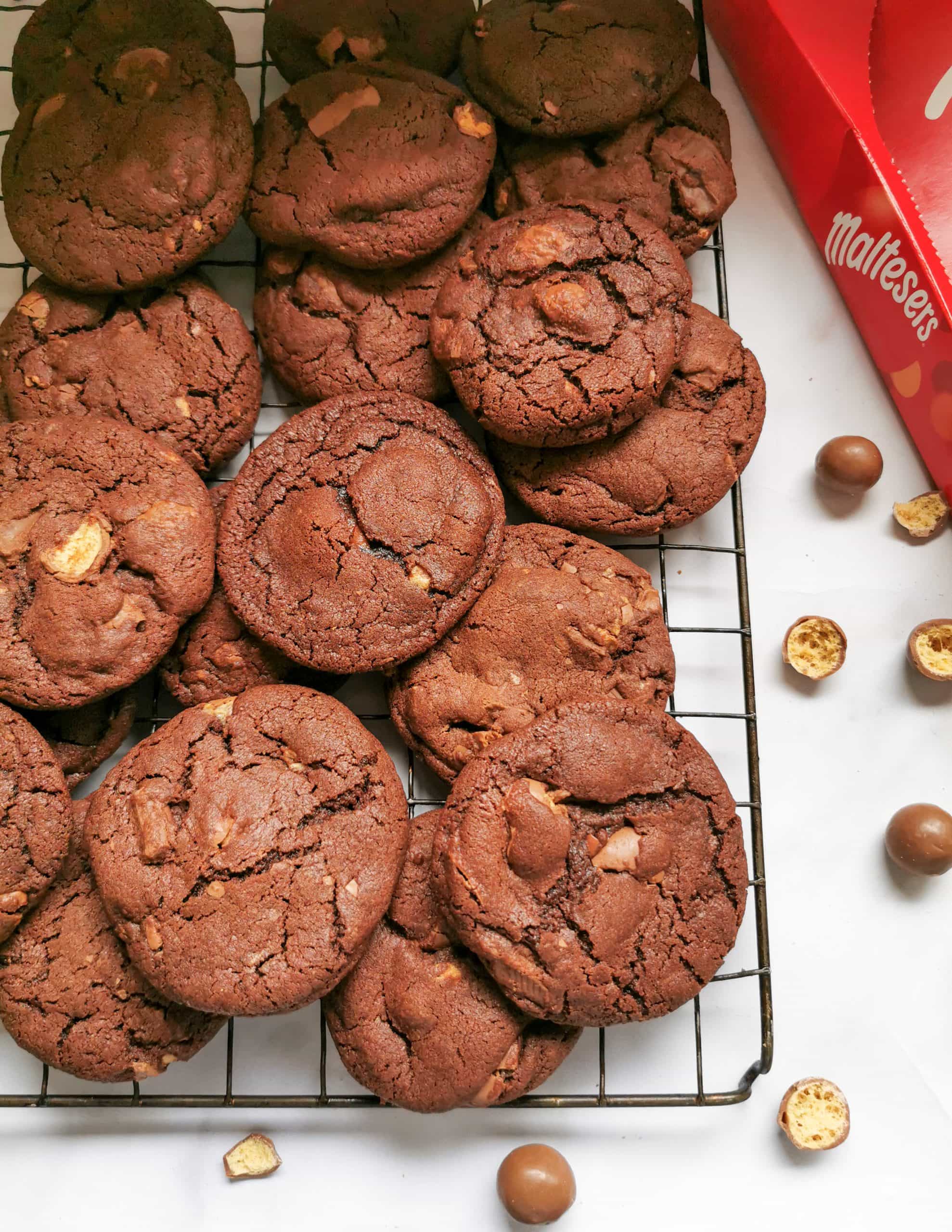 Chococolate cookies with Maltesers on a black wire rack.