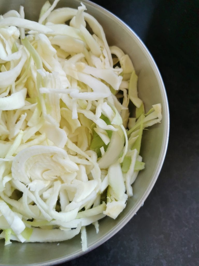 A sliver bowl of sliced white cabbage