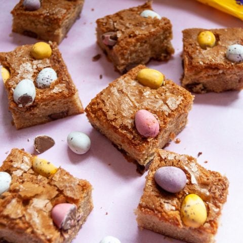 Mini egg blondies on a pink background.