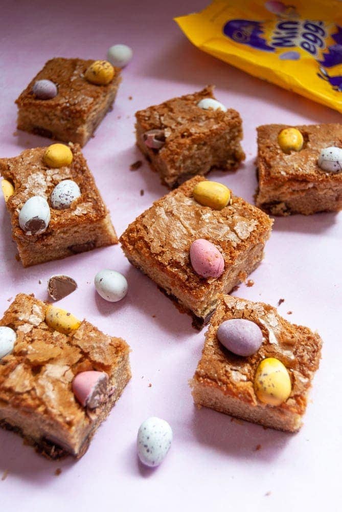 Mini egg blondies on a pink background.