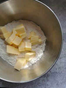 A silver bowl of flour and cubed butter