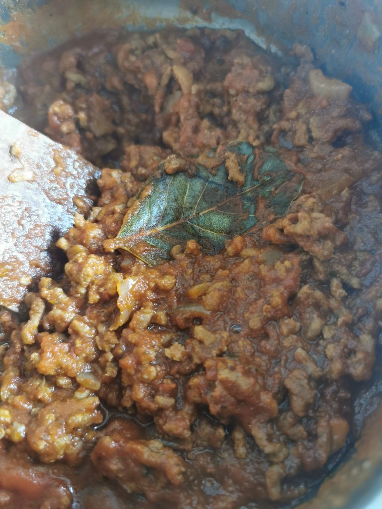 A pan of beef ragu with bay leaves