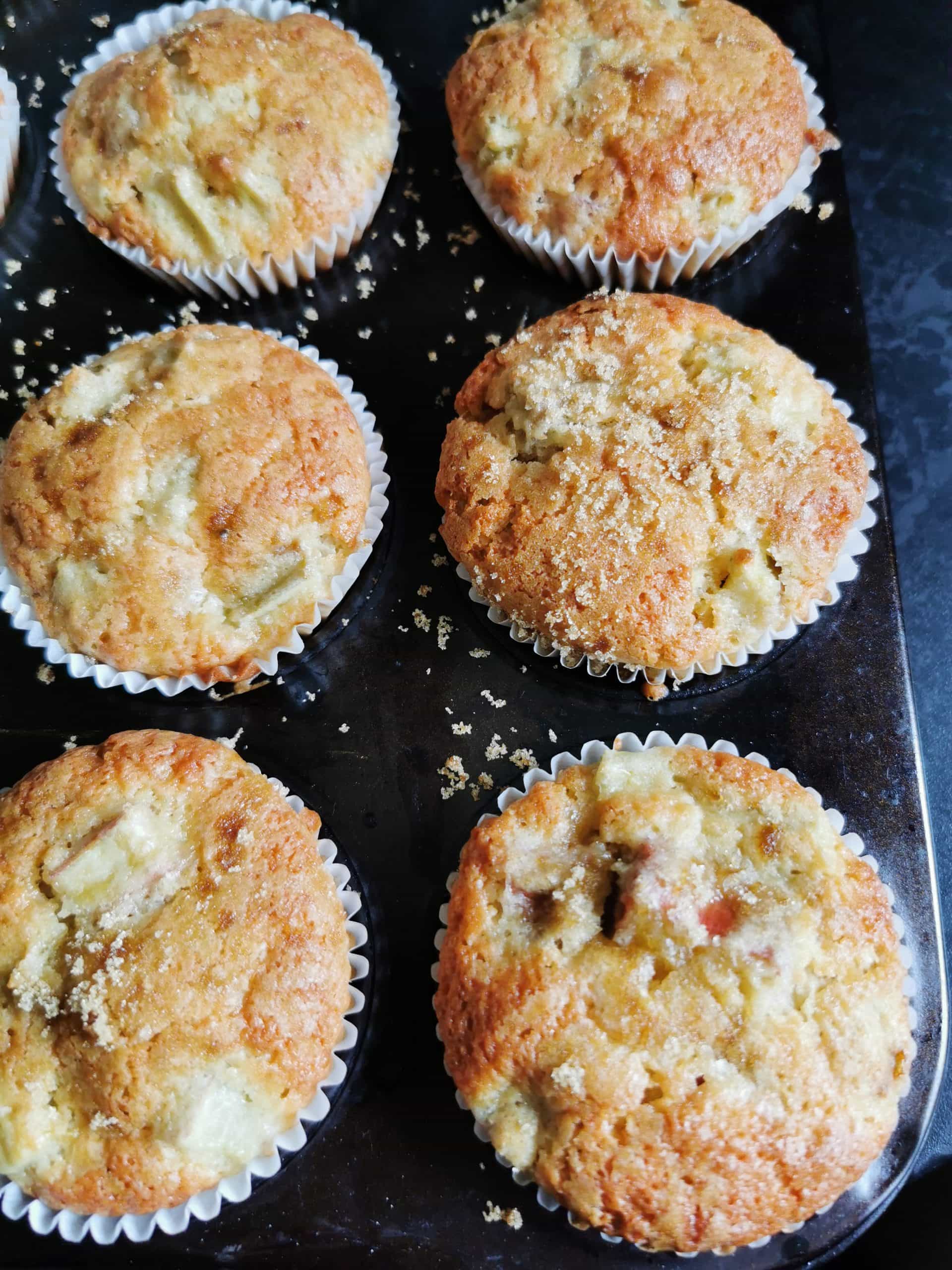 A freshly baked batch of rhubarb muffins in a black muffin tin.