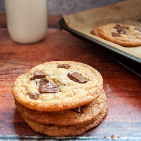 A stack of cookies with chocolate chunks on a wooden background