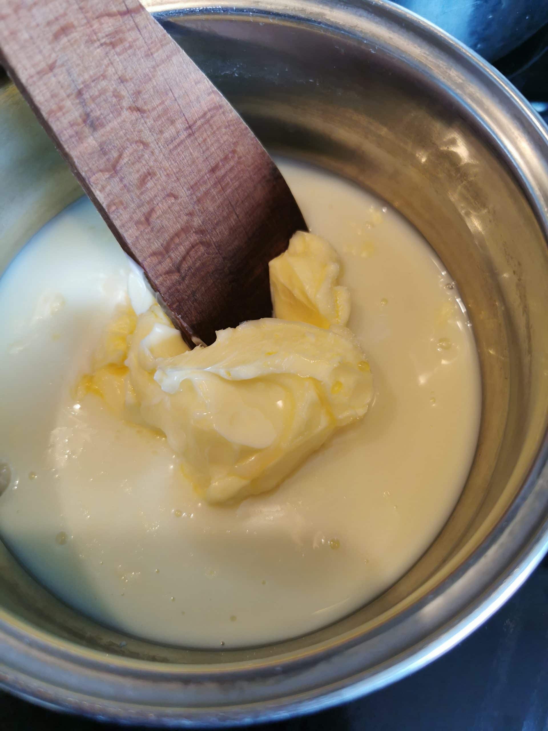 a pan and a wooden spoon with condensed milk, sugar and butter