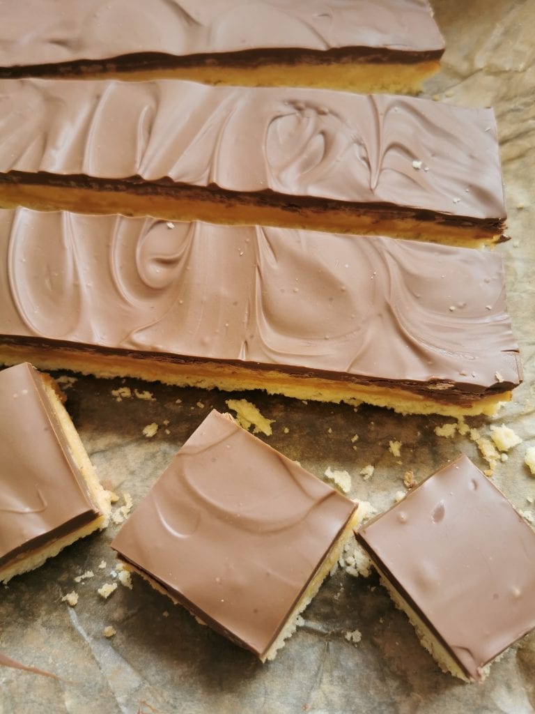 Millionaires shortbread slices on pieces of baking paper