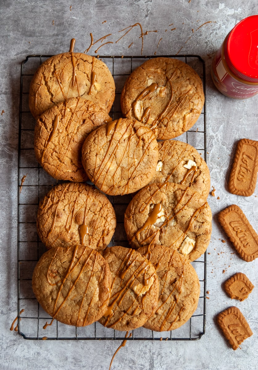 A flat lay photo of a wire rack with Biscoff cookies drizzled with Biscoff spread on a grey background