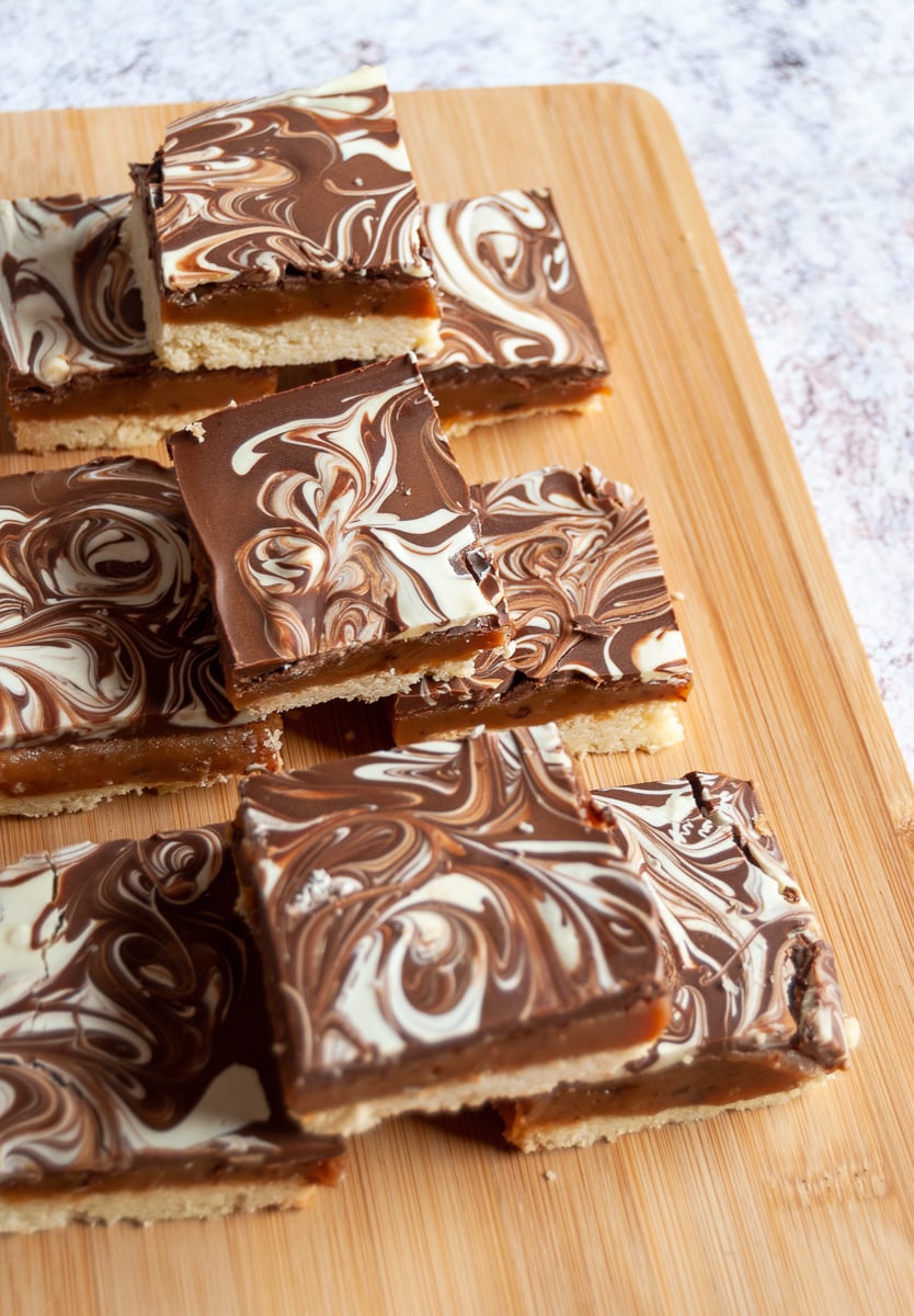 squares of white and milk chocolate swirled millionaires shortbread on a wooden board