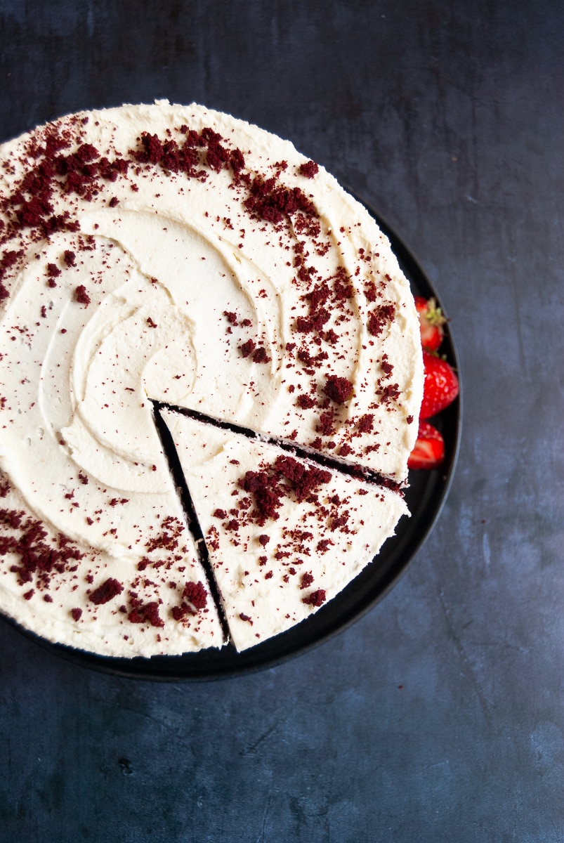 A flat lay photo of a red velvet cake on a black plate