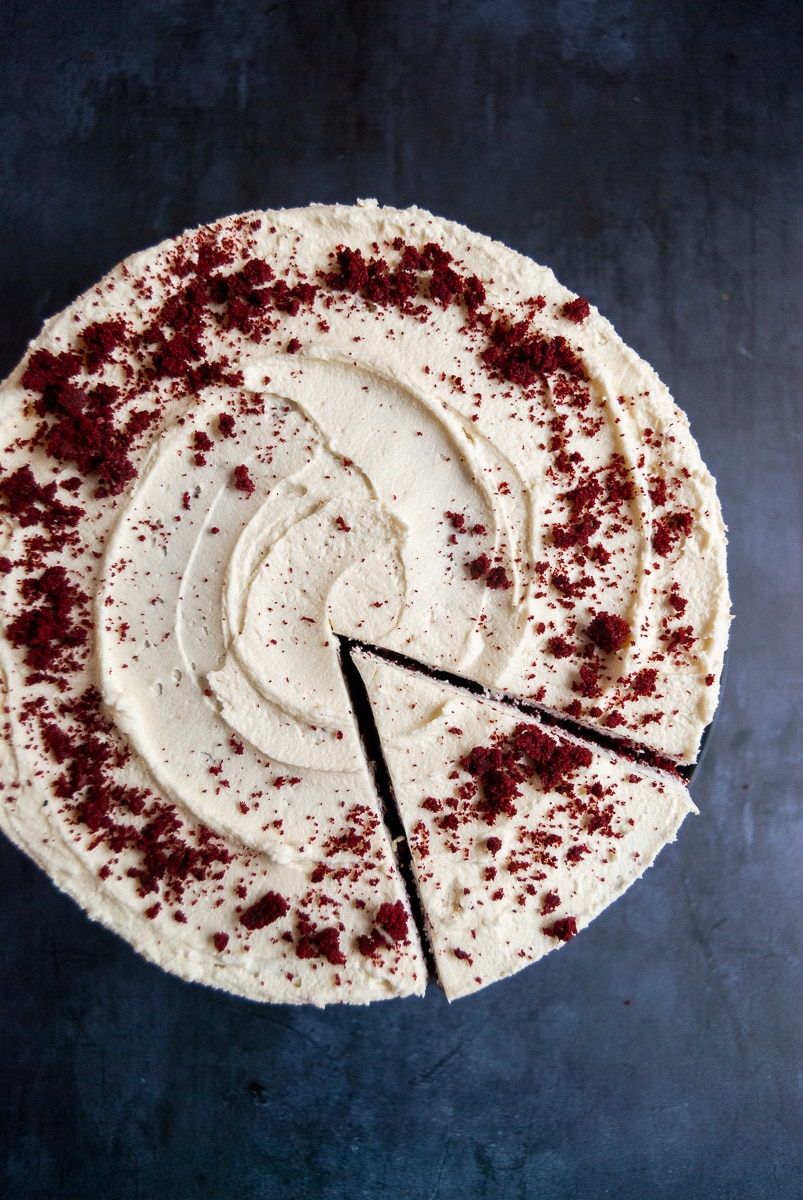 A flat lay photo of a red velvet cake on a black plate 