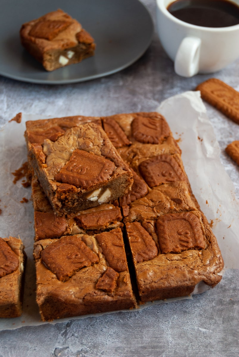 Biscoff blondies, a plate with a blondie, a cup of coffee and Lotus biscuits