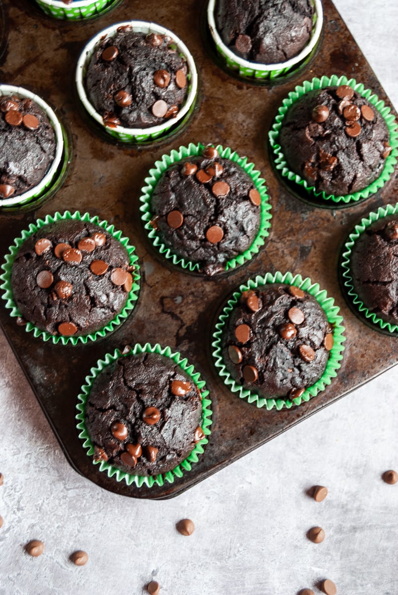 A batch of chocolate zucchini muffins in a rustic looking muffin pan