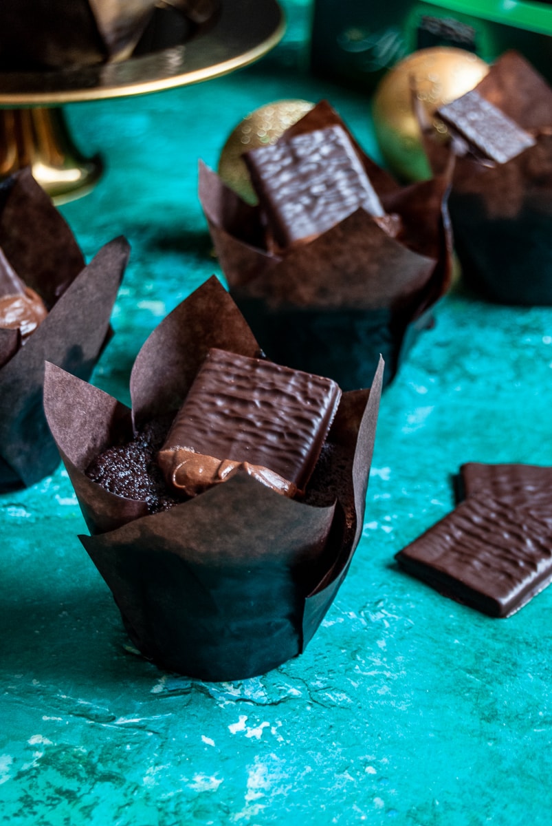 a chocolate muffin topped with chocolate ganache and an after eight chocolate on a green background