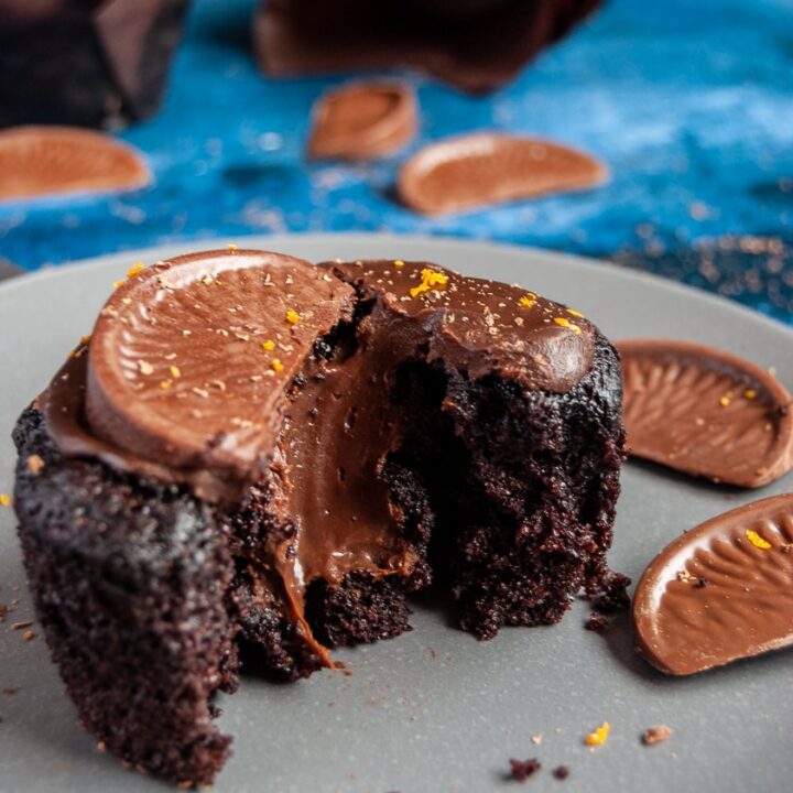 a chocolate muffin on a grey plate, broken in half to reveal a molten chocolate ganache middle.