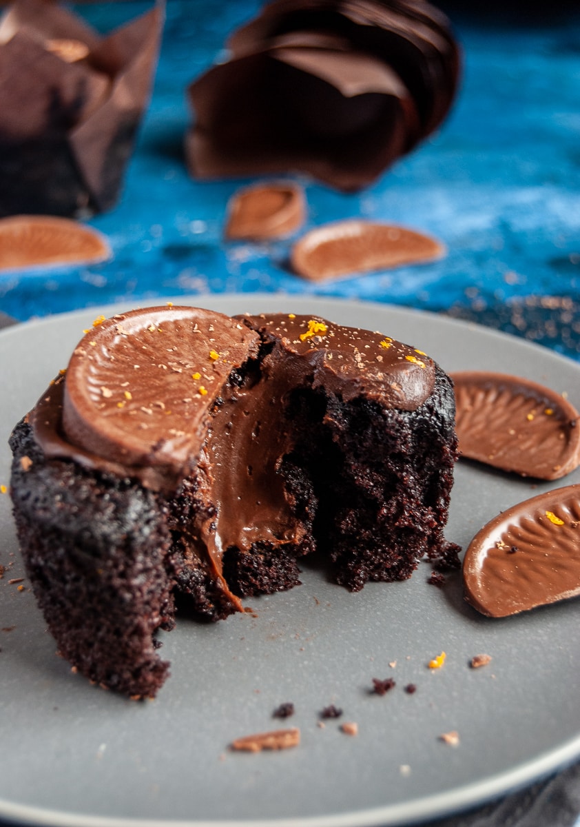 a chocolate muffin on a grey plate, broken in half to reveal a molten chocolate ganache middle. 