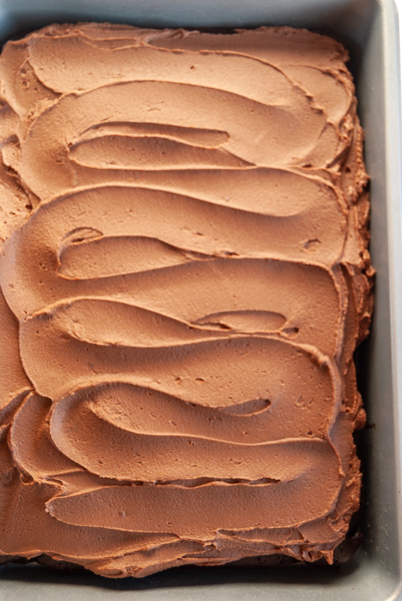 A chocolate sheet cake covered in chocolate ganache in a silver baking pan