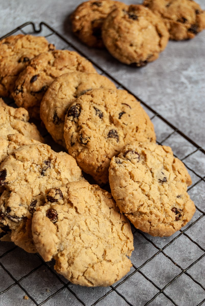 A batch of oat and raisin cookies on a black wire cooling rack