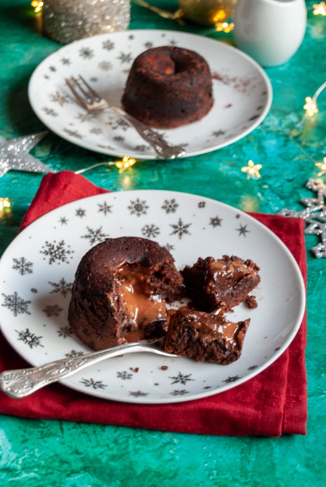 two mini chocolate puddings  cut iin half with a fork to reveal the molten chocolate middle, a red napkin and gold fairy lights