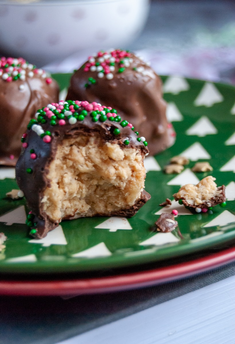 a close up photo of a chocolate peanut butter truffle with red, white and green sprinkles on a green and white plate