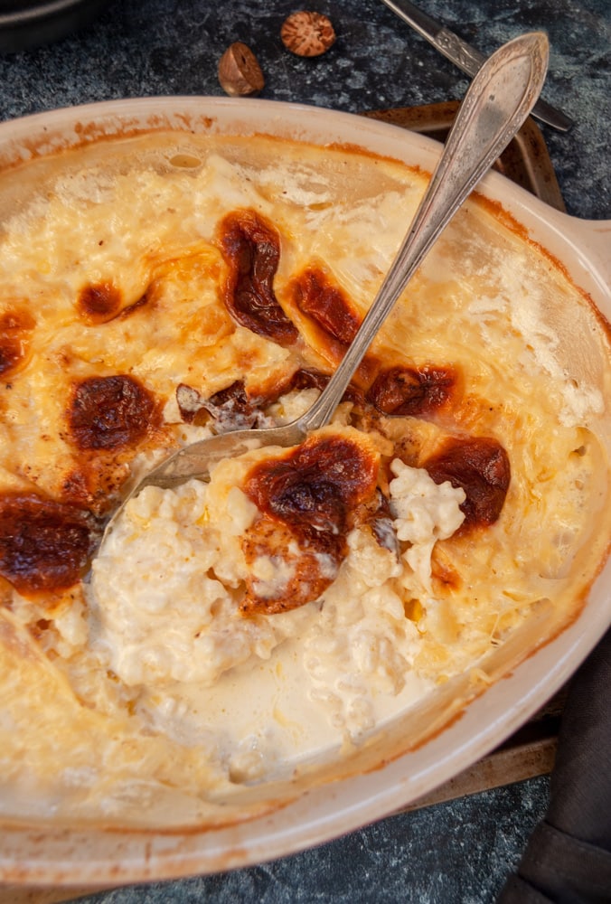 A dish of creamed rice pudding with a large silver spoon. 