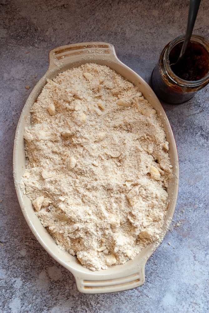 an unbaked apple crumble in an oval dish and a jar of mincemeat