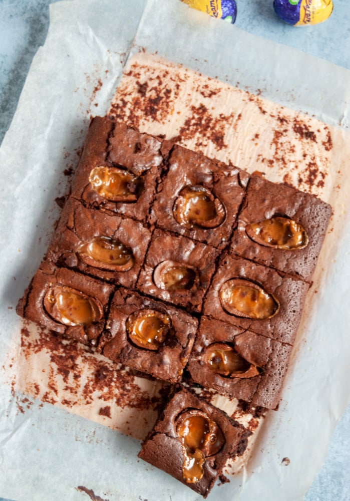 a batch of chocolate brownies with a caramel egg filling on a piece of baking paper.