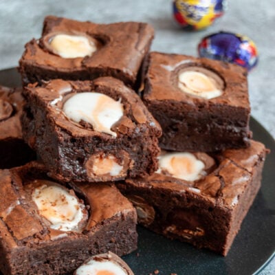 a black plate of chocolate brownies topped with creme eggs.