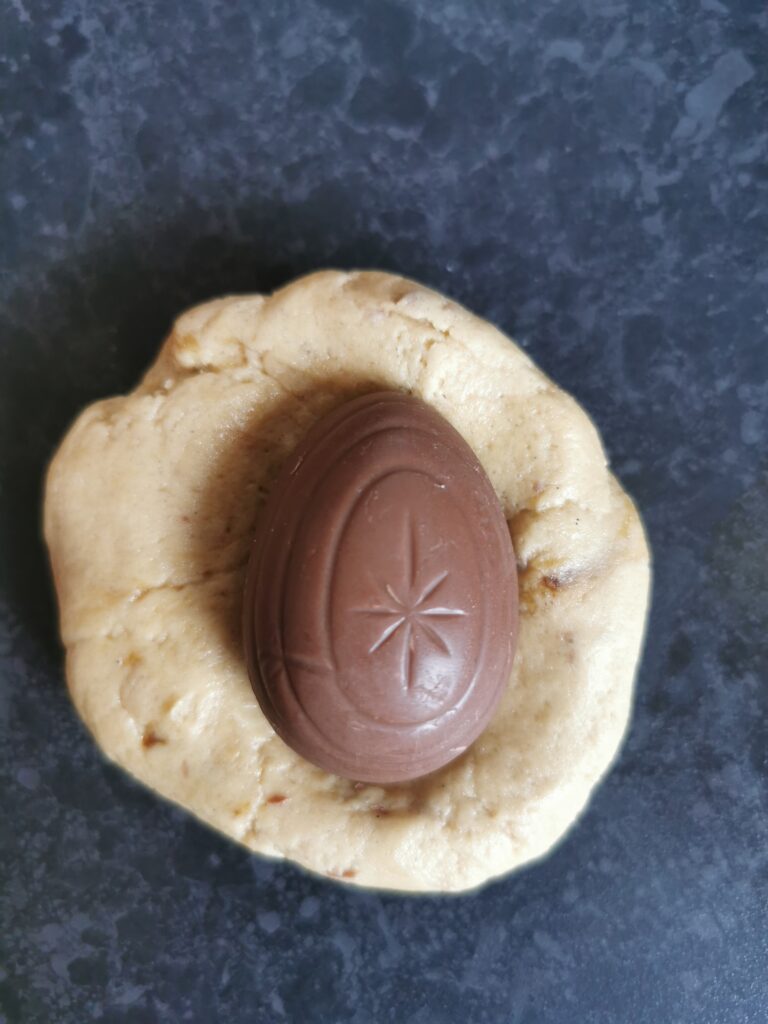 A large piece of cookie dough with a creme egg in the middle