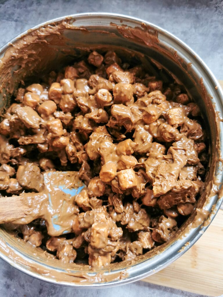 A silver saucepan of melted biscoff spread, chocolate and marshmallows.