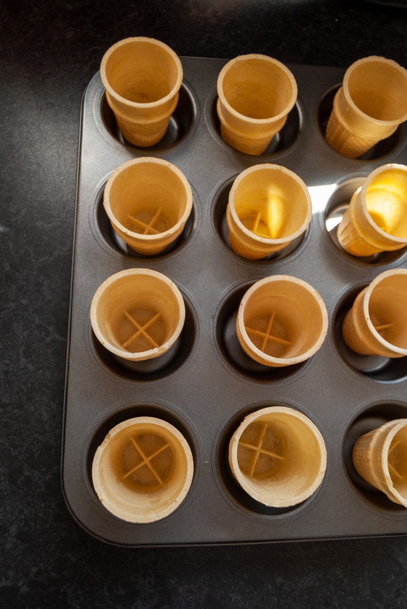 a muffin tin filled with flat bottomed ice cream cones