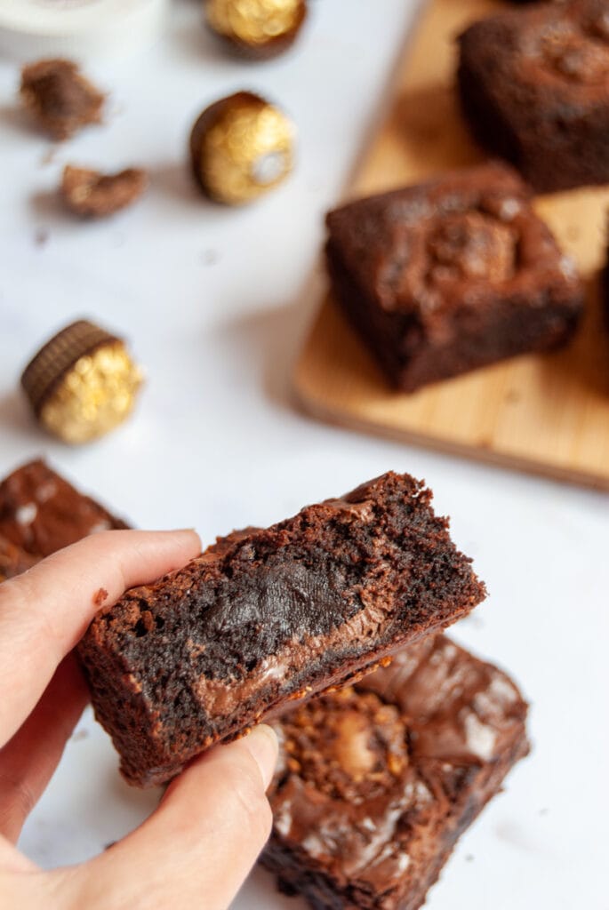 a hand holding a chocolate brownie filled with Nutella.