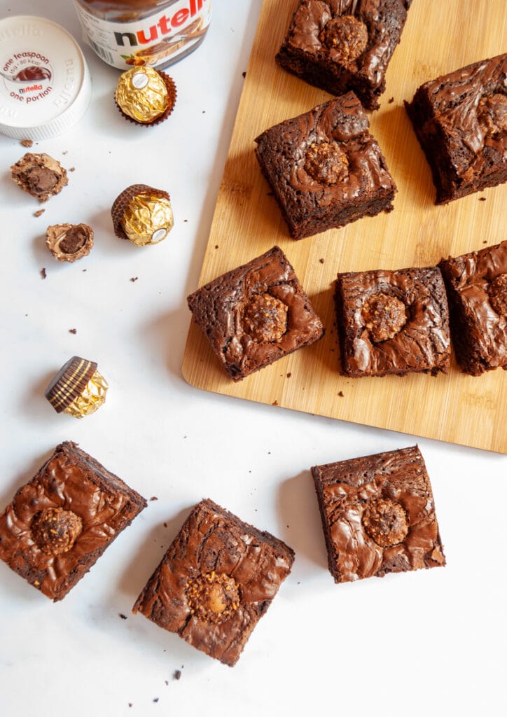 chocolate brownies with Nutella on a white background and wooden board.