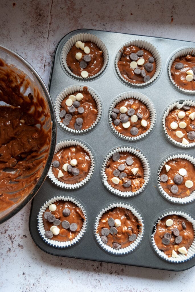 a silver muffin pan filled with chocolate chip muffin batter