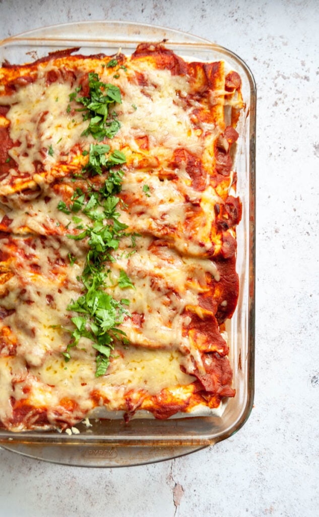 a pyrex dish of Enchiladas sprinkled with freshly chopped parsley.