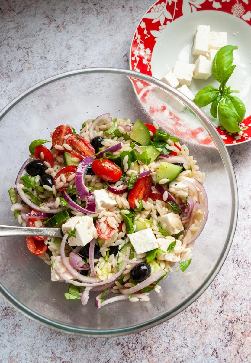 a Greek pasta salad in a large glass bowl.