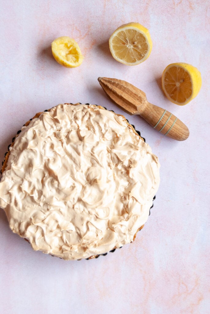 a lemon meringue pie on a pink backdrop.
