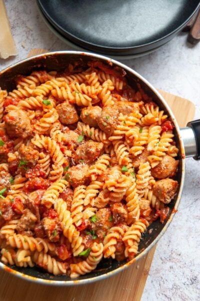 a saucepan of pasta twists and a sausage tomato sauce.