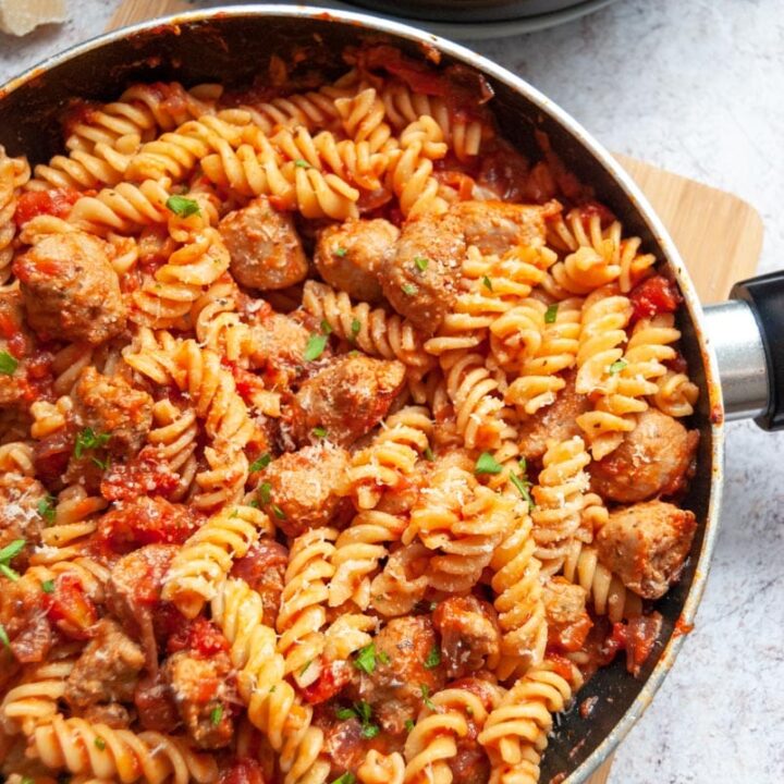 a saucepan of pasta twists and a sausage tomato sauce.