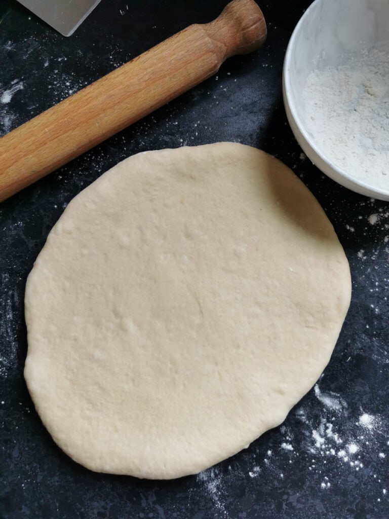 a piece of dough rolled out on a floured work surface with a rolling pin.