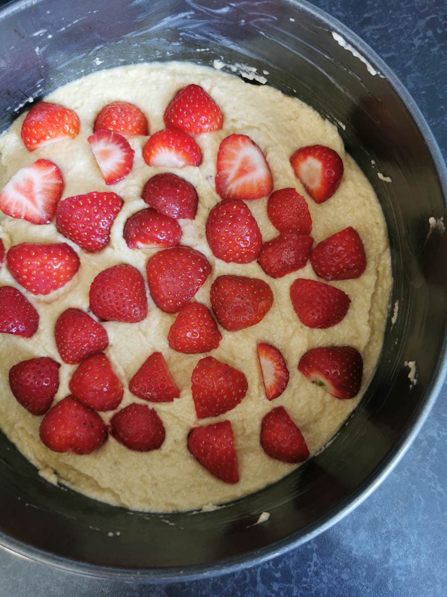 An unbaked cake topped with fresh strawberries